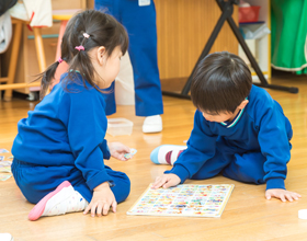 床に座って英語のボ－ドを見る子どもたち